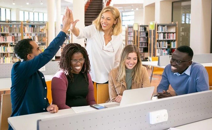 ESL students celebrating with a high-five around a library table