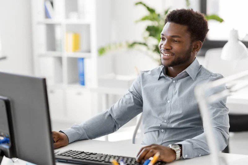 A friendly staff member smiling at a computer, ready to respond to messages